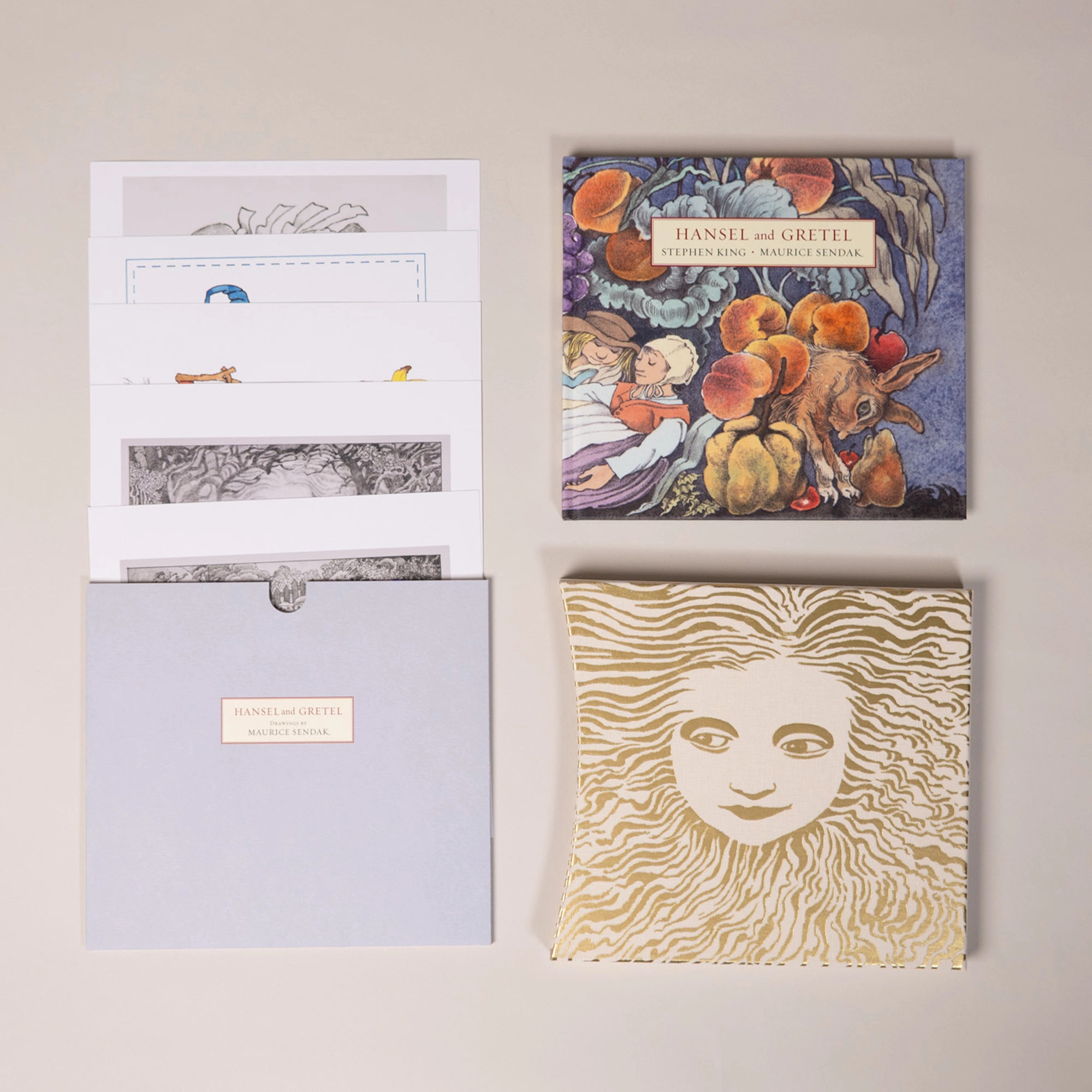All of the elements of the deluxe edition laid out side by side, including slipcase, hardback edition, prints and envelope.